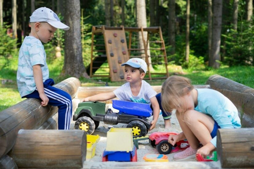 Drei Kinder spielen gemeinsam in einem Sandkasten im Wald